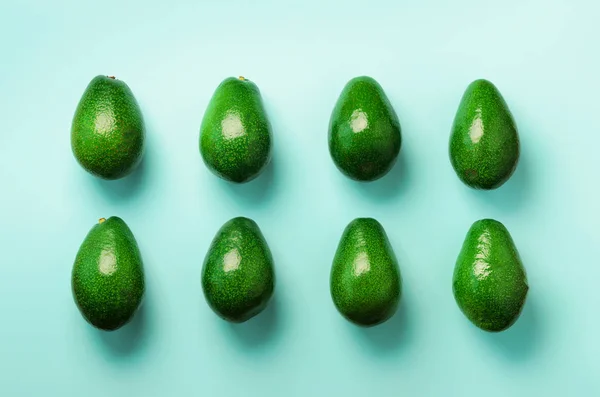 Mavi zemin üzerine yeşil avokado desen. Üstten görünüm. Pop sanat tasarım, yaratıcı yaz gıda kavramı. Organik avocadoes en az daire yatıyordu tarzı. — Stok fotoğraf