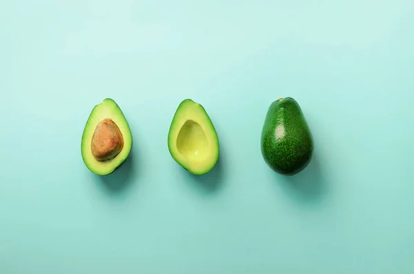 Organik avokado tohumu, avokado yarısı ve mavi arka plan üzerinde tüm meyve ile. Üstten görünüm. Pop sanat tasarım, yaratıcı yaz gıda kavramı. Yeşil avocadoes desen en az daire yatıyordu tarzı. — Stok fotoğraf