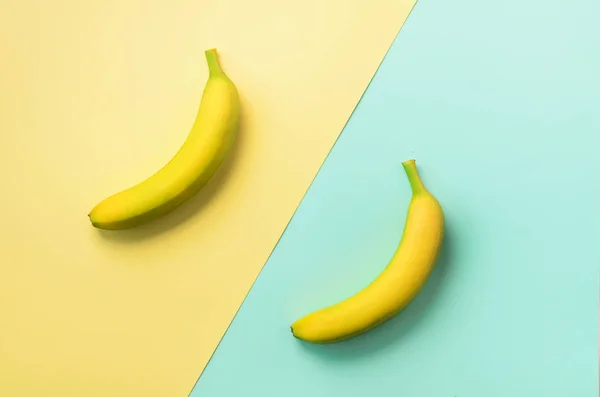 Plátanos sobre fondo azul y amarillo. Patrón de fruta colorido con espacio de copia. Vista superior. Diseño de arte pop, concepto creativo de verano. Banner. Plátano en estilo laico plano minimalista . — Foto de Stock