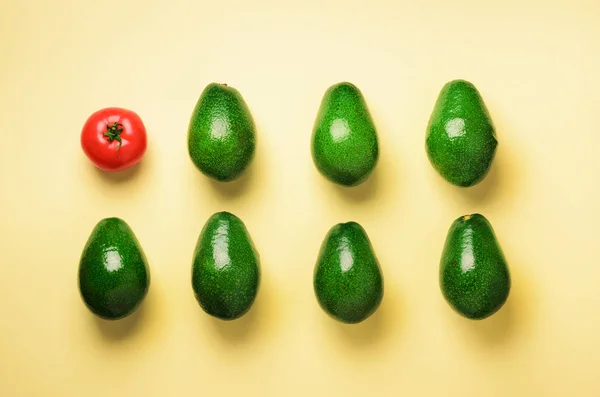 Органічний авокадо, помідор на синьо-жовтому тлі. Вид зверху. Поп-арт-дизайн, креативна концепція літньої їжі. Рослинний візерунок в мінімальному стилі плоского шару . — стокове фото