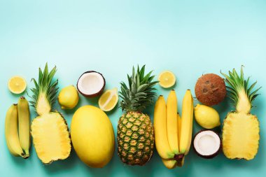 Mavi arka plan üzerinde taze organik sarı meyve. Tek renkli kavramı ile muz, Hindistan cevizi, ananas, limon, kavun. Üstten görünüm. Uzay kopyalayın. Pop sanat tasarım, yaratıcı yaz tasarım. Vegan gıda. Düz yatıyordu