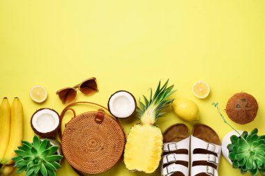 Şık rattan meyve güneşli arka plan üzerinde çanta, Hindistan cevizi, birkenstocks, etli, güneş gözlüğü ve sarı. Afiş. Üstten görünüm kopya alanı ile. Trendy bambu çanta ve beyaz ayakkabı. Yaz moda düz yatıyordu