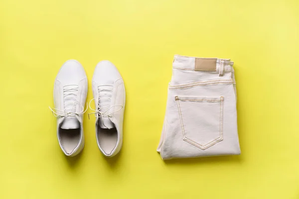 Female white sneakers and jeans on yellow background with copy space. Top view. Summer fashion, shopping, capsule wardrobe concept. Creative flat lay. Modern and casual outfit. — Stock Photo, Image