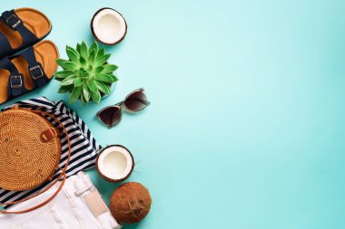 Kadın birkenstock sandalet, kot, tişört, rattan çanta, Hindistan cevizi ve güneş gözlüğü kopya alanı ile mavi arka plan üzerinde çizgili. Üstten görünüm. Yaz modası, kapsül gardırop kavramı. Yaratıcı düz lay.
