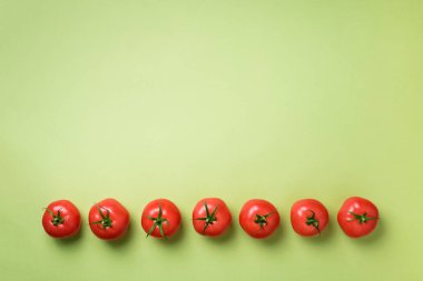 Satır yeşil zemin üzerine taze kırmızı domates. Üstten görünüm. Uzay kopyalayın. Minimal tasarım. Vejetaryen, vegan, organik gıda ve alkali yemek kavramı