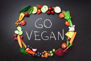Sağlıklı gıda arka plan. Daire taze sebze, meyve, fındık, çilek el yazısı ile siyah kara tahta gitmek Vegan ifade. Üstten görünüm. Vejetaryen, vegan, detoks ve temiz yemek kavramı