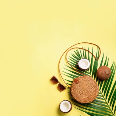 Rattan çanta, Hindistan cevizi, birkenstocks, hurma dalları güneş gözlüğü üzerinde arka plan sarı. Kare ürün. Görünümü en çok, uzay kopyalayın. Trendy bambu çanta ve ayakkabılar. Yaz moda düz yatıyordu. Gezi, tatil kavramı