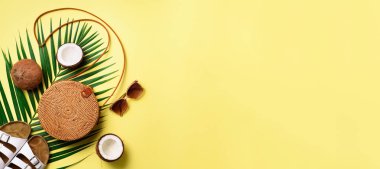 Şık rattan çanta, Hindistan cevizi, birkenstocks, hurma dalları, sarı zemin üzerine güneş gözlüğü. Afiş. Üstten görünüm kopya alanı ile. Trendy bambu çanta ve beyaz ayakkabı. Yaz moda düz yatıyordu