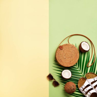 Şık rattan çanta, Hindistan cevizi, birkenstocks, hurma dalları, zeytin yeşil arka plan üzerinde güneş gözlüğü. Kare ürün. Görünümü en çok, uzay kopyalayın. Trendy bambu çanta ve beyaz ayakkabı. Yaz moda düz yatıyordu