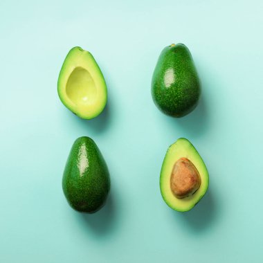 Organik avokado tohumu, avokado yarısı ve mavi arka plan üzerinde tüm meyve ile. Üstten görünüm. Pop sanat tasarım, yaratıcı yaz gıda kavramı. Yeşil avocadoes desen en az daire yatıyordu tarzı.