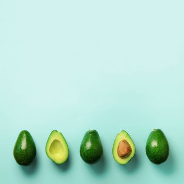 Organik avokado tohumu, avokado yarısı ve mavi arka plan üzerinde tüm meyve ile. Üstten görünüm. Kare ürün. Pop sanat tasarım, yaratıcı yaz gıda kavramı. Yeşil avocadoes desen en az daire yatıyordu tarzı.