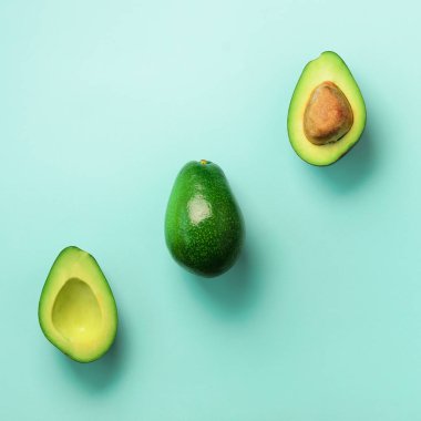 Organik avokado tohumu, avokado yarısı ve mavi arka plan üzerinde tüm meyve ile. Üstten görünüm. Pop sanat tasarım, yaratıcı yaz gıda kavramı. Yeşil avocadoes desen en az daire yatıyordu tarzı.