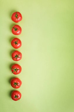 Satır yeşil zemin üzerine taze kırmızı domates. Üstten görünüm. Uzay kopyalayın. Minimal tasarım. Vejetaryen, vegan, organik gıda ve alkali yemek kavramı