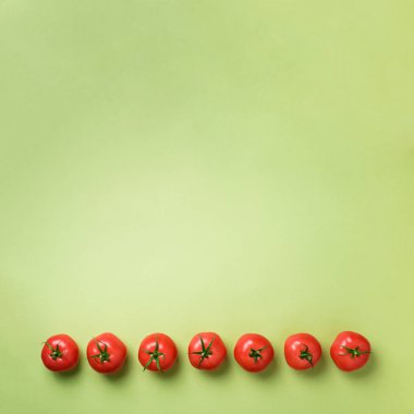 Satır yeşil zemin üzerine taze kırmızı domates. Üstten görünüm. Uzay kopyalayın. Minimal tasarım. Vejetaryen, vegan, organik gıda ve alkali yemek kavramı