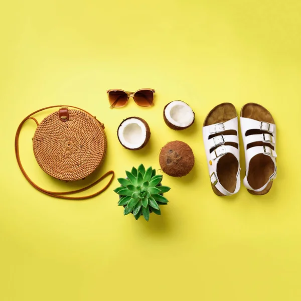 Stylish rattan bag, coconut, birkenstocks, palm branches, sunglasses on yellow background. Square crop. Top view with copy space. Trendy bamboo bag and white shoes. Summer fashion flat lay — Stock Photo, Image