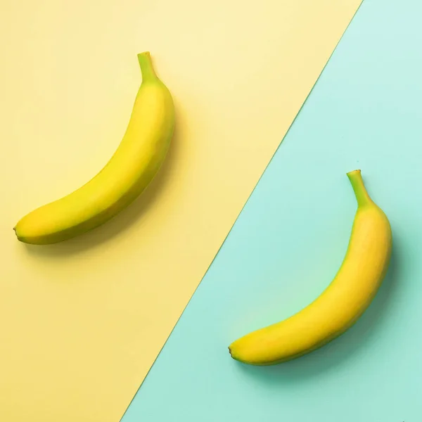 Plátanos sobre fondo azul y amarillo. Patrón de fruta colorido con espacio de copia. Vista superior. Diseño de arte pop, concepto creativo de verano. Banner. Plátano en estilo laico plano minimalista . — Foto de Stock