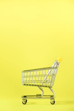Alışveriş sepeti sarı zemin üzerine. Minimalizm tarzı. Yaratıcı tasarım. Uzay kopyalayın. Süpermarkette alışveriş arabası. Satış, iskonto, shopaholism kavramı. Tüketici Derneği eğilim