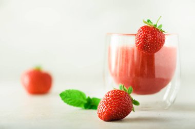 Cam kopya alanı ile gri arka plan üzerinde kırmızı çilek milkshake. Yaz gıda kavramı, vegan diyet. Taze çilek ile pembe yüzlü