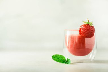 Cam kopya alanı ile gri arka plan üzerinde kırmızı çilek milkshake. Yaz gıda kavramı, vegan diyet. Taze çilek ile pembe yüzlü