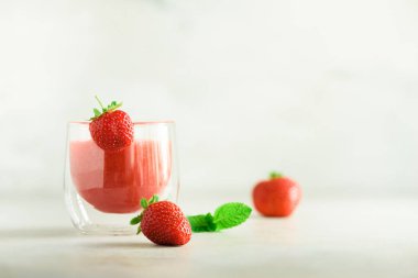 Cam kopya alanı ile gri arka plan üzerinde kırmızı çilek milkshake. Yaz gıda kavramı, vegan diyet. Taze çilek ile pembe yüzlü