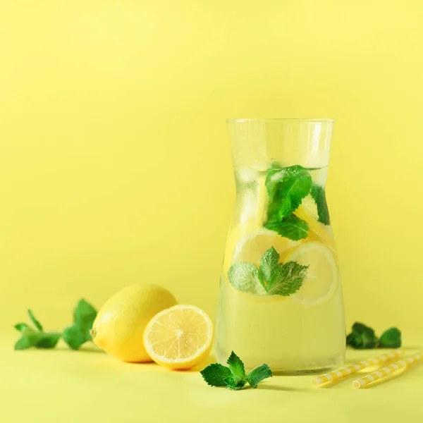 Fresh summer fruits water or lemonade with mint, ice, lemon on yellow background. Square crop. Copy space. Summer infused water. Citrus flavored beverage. — Stock Photo, Image