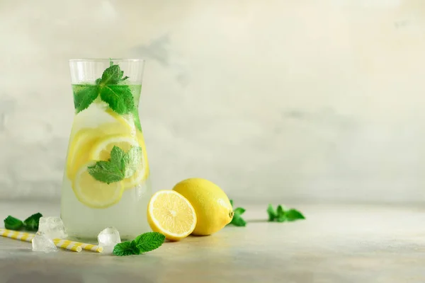 La limonada cítrica - el agua fría con el hielo, la menta, el limón sobre el fondo gris. Bebida desintoxicante. Fruta de verano infundido agua. Copiar espacio . — Foto de Stock