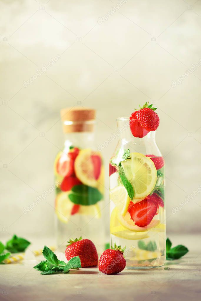 Strawberry detox water with mint, lemon on grey background. Citrus lemonade. Summer fruit infused water. Copy space