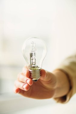 Ampul kopya alanı ile krem arka planda tutan kadın el. Yaratıcı bir fikir, yeni iş planı, motivasyon, yenilik, ilham kavramı.
