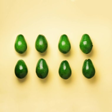 Sarı zemin üzerine yeşil avokado desen. Kare ürün. Üstten görünüm. Pop sanat tasarım, yaratıcı yaz gıda kavramı. Organik avocadoes en az daire yatıyordu tarzı.
