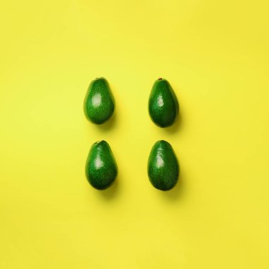 Sarı zemin üzerine yeşil avokado desen. Kare ürün. Üstten görünüm. Pop sanat tasarım, yaratıcı yaz gıda kavramı. Organik avocadoes en az daire yatıyordu tarzı.