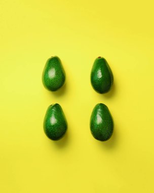 Sarı zemin üzerine yeşil avokado desen. Üstten görünüm. Pop sanat tasarım, yaratıcı yaz gıda kavramı. Organik avocadoes en az daire yatıyordu tarzı.