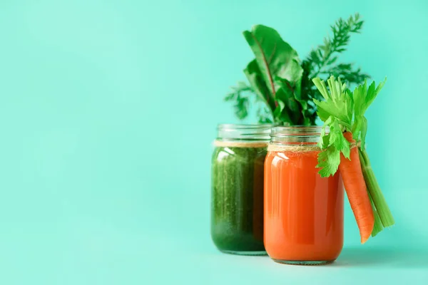 Здоровые органические зеленые и оранжевые коктейли на голубом фоне. Детоксикационные напитки в стеклянной банке из овощей - морковь, сельдерей, свекловичная зелень и топы. Принято. Концепция летней еды — стоковое фото