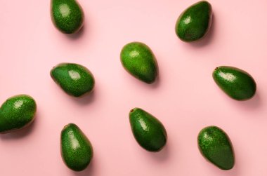 Pembe bir arka plan üzerinde avokado desen. Üstten Görünüm. Afiş. Pop sanat tasarım, yaratıcı yaz gıda kavramı. Yeşil avocadoes, en az düz stil yatıyordu.