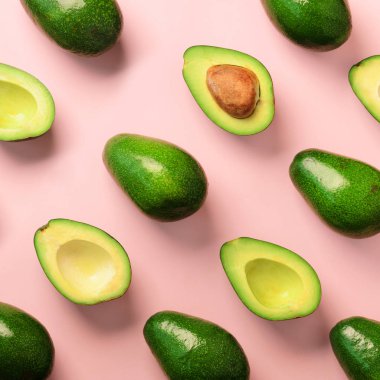 Pembe bir arka plan üzerinde avokado desen. Üstten Görünüm. Afiş. Pop sanat tasarım, yaratıcı yaz gıda kavramı. Yeşil avocadoes, en az düz stil yatıyordu. Kare kırpma.