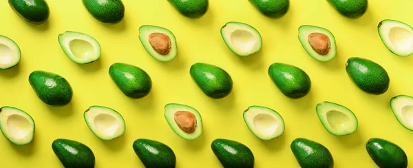 Avocado pattern on yellow background. Top view. Banner. Pop art design, creative summer food concept. Green avocadoes, minimal flat lay style. Banner.