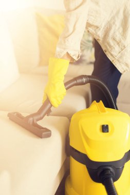 Kadın kanepe sarı elektrikli süpürge ile temizlik. Uzay kopyalayın. Temizlik konsepti.