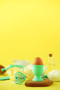 Malzemeler - tereyağı, şeker, un, yumurta, yağ, kaşık, fırça, çırpma teli, süt sarı arka plan üzerinde pişirme sağlıklı. Afiş. Ekmek yiyecek çerçeve, etli bitki konseptiyle yemek. Kopya alanı