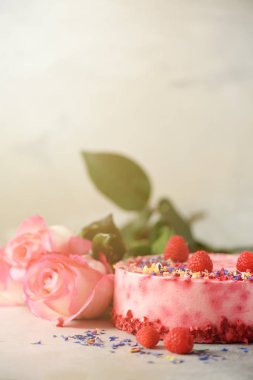Pembe güller ve taze çilek, biberiye, beton zemin üzerine kuru çiçekler ile Ahududu cake. Alan metni kopyalayın. Doğum günü partisi konsepti.