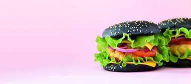 Fast food afiş. Sığır eti, peynir, marul, soğan, domates pembe bir arka plan üzerinde sulu et burger. Yemek götürün. Sağlıksız beslenme kavramı ve kopya alanı.