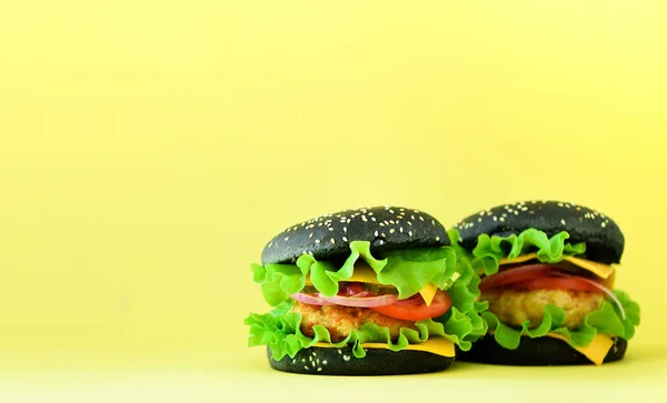 Fast food frame. Delicious meat burgers on yellow background. Take away meal. Unhealthy diet concept with copy space.