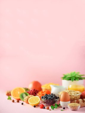 Kahvaltı servisi yumuşak haşlanmış yumurta, yulaf gevreği, fındık, meyve, çilek, süt, yoğurt, portakal, muz, pembe arka plan şeftali. Sağlıklı gıda diyet