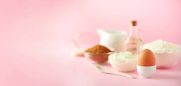 Banner with copy space. Bakery food frame, cooking concept. Different baking ingredients - butter, sugar, flour, milk, eggs, oil, spoon, rolling pin, brush, whisk over pink background