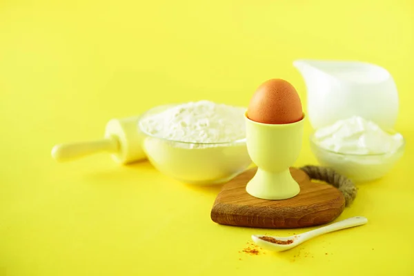 Healthy baking ingredients - butter, sugar, flour, eggs, oil, spoon, rolling pin, brush, whisk, milk over yellow background. Bakery food frame, cooking concept. Copy space