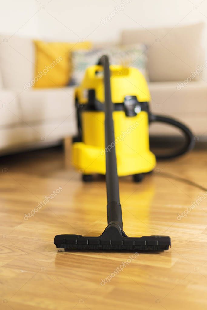 Woman in protective gloves cleaning the living room with yellow vacuum cleaner. Copy space. Clean concept.