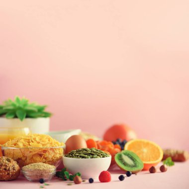 Sağlıklı kahvaltı malzemeleri. Kare mahsul. Yulaf ve mısır gevreği, yumurta, fındık, meyve, böğürtlen, tost, süt, yoğurt turuncu muz şeftalisi pembe arka planda kopyalama alanı
