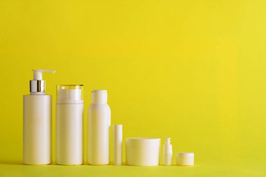 Kopya alanı Sarı zemin üzerine beyaz kozmetik tüpler. Cilt Bakımı, vücut bakımı, güzellik kavramı. Afiş