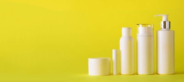 Kopya alanı Sarı zemin üzerine beyaz kozmetik tüpler. Cilt Bakımı, vücut bakımı, güzellik kavramı. Afiş
