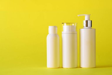 Sarı arka planda beyaz kozmetik tüpleri ve fotokopi alanı. Cilt bakımı, vücut bakımı, güzellik konsepti.