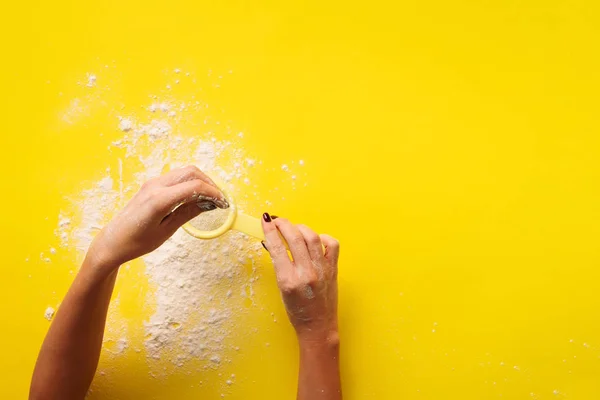 Female hand holding sieve flour on yellow background. Baking and cooking concept. Banner with copy space. — 스톡 사진