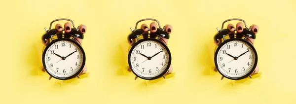 黄色い紙の背景に穴を通って黒い目覚まし時計を保持する手のシームレスなパターン。警告の概念を起こせ朝のルーティンミニマルスタイルのデザイン. — ストック写真